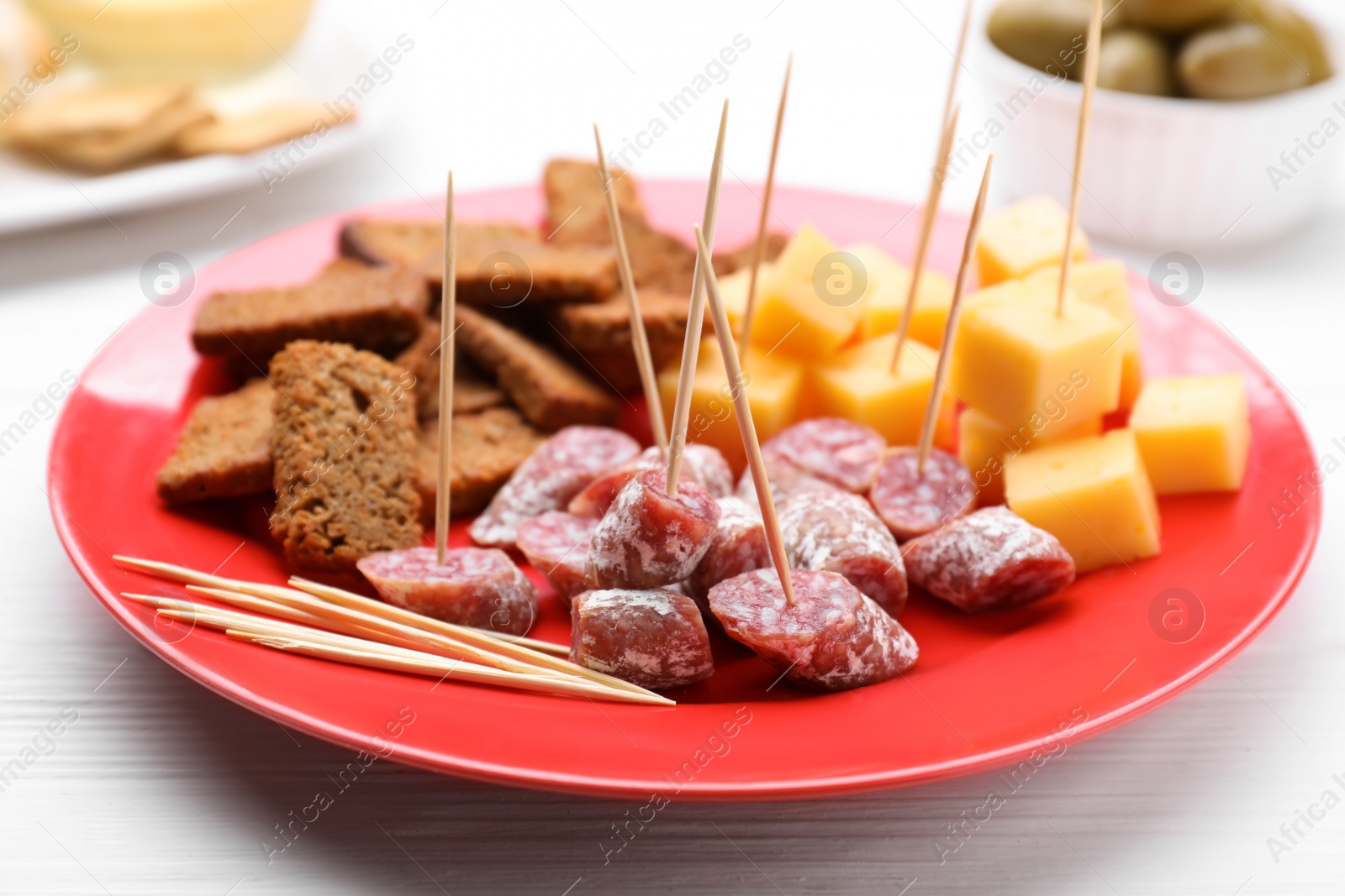 Photo of Toothpick appetizers. Pieces of sausage, cheese and croutons on white wooden table