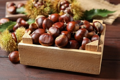 Fresh sweet edible chestnuts in crate on wooden table