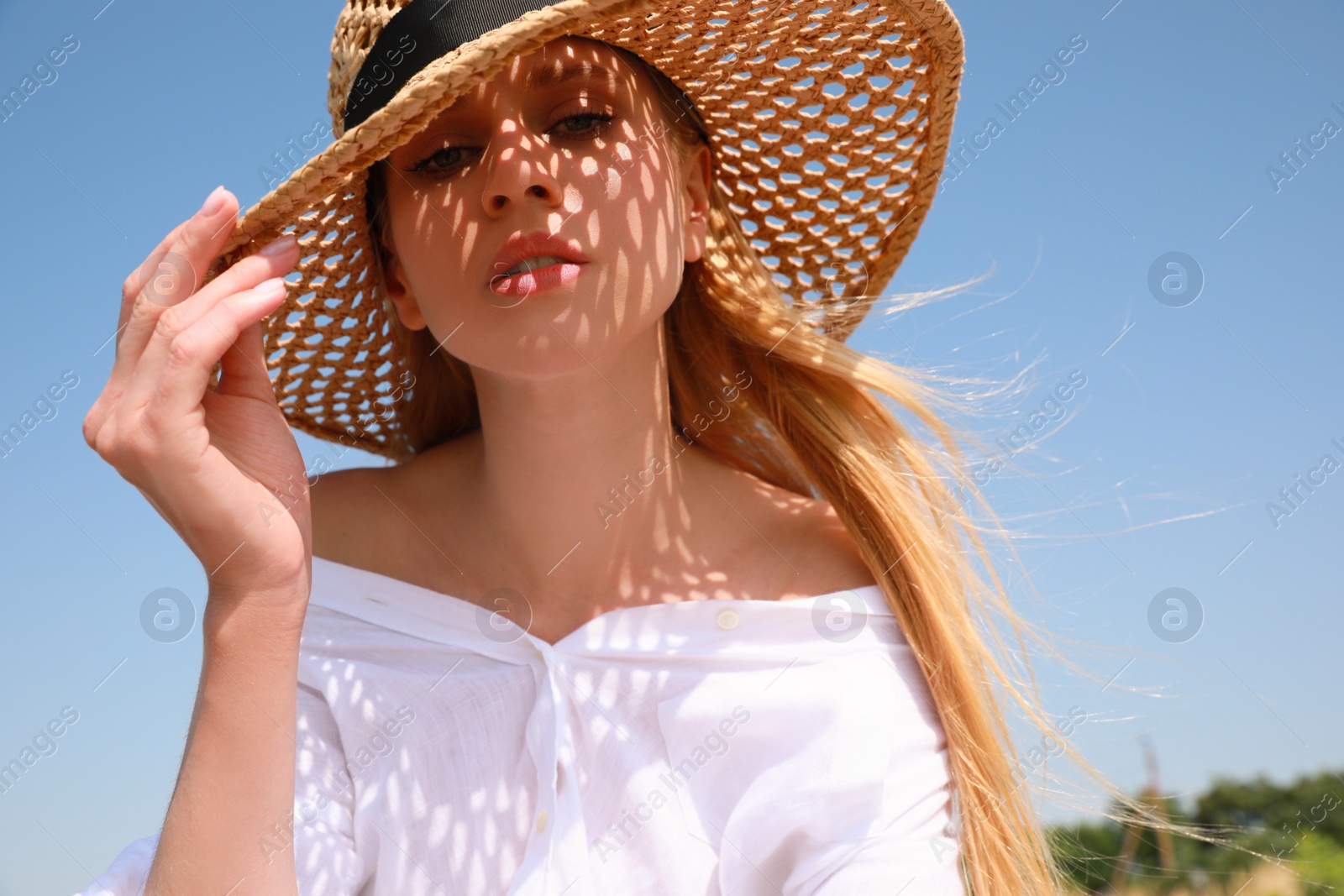 Photo of Beautiful woman with straw hat against blue sky on sunny day