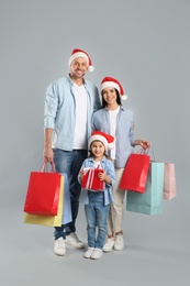 Photo of Happy family with paper bags and gift on grey background. Christmas shopping
