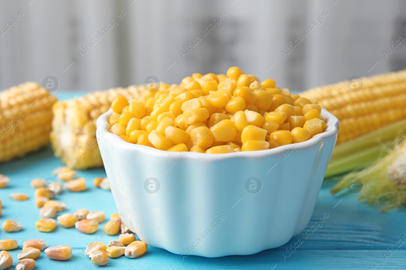 Photo of Bowl with corn kernels on blue wooden table