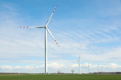 Photo of Modern wind turbines in field on sunny day. Alternative energy source
