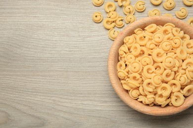 Photo of Raw dischi volanti pasta in bowl on light grey wooden table, top view. Space for text