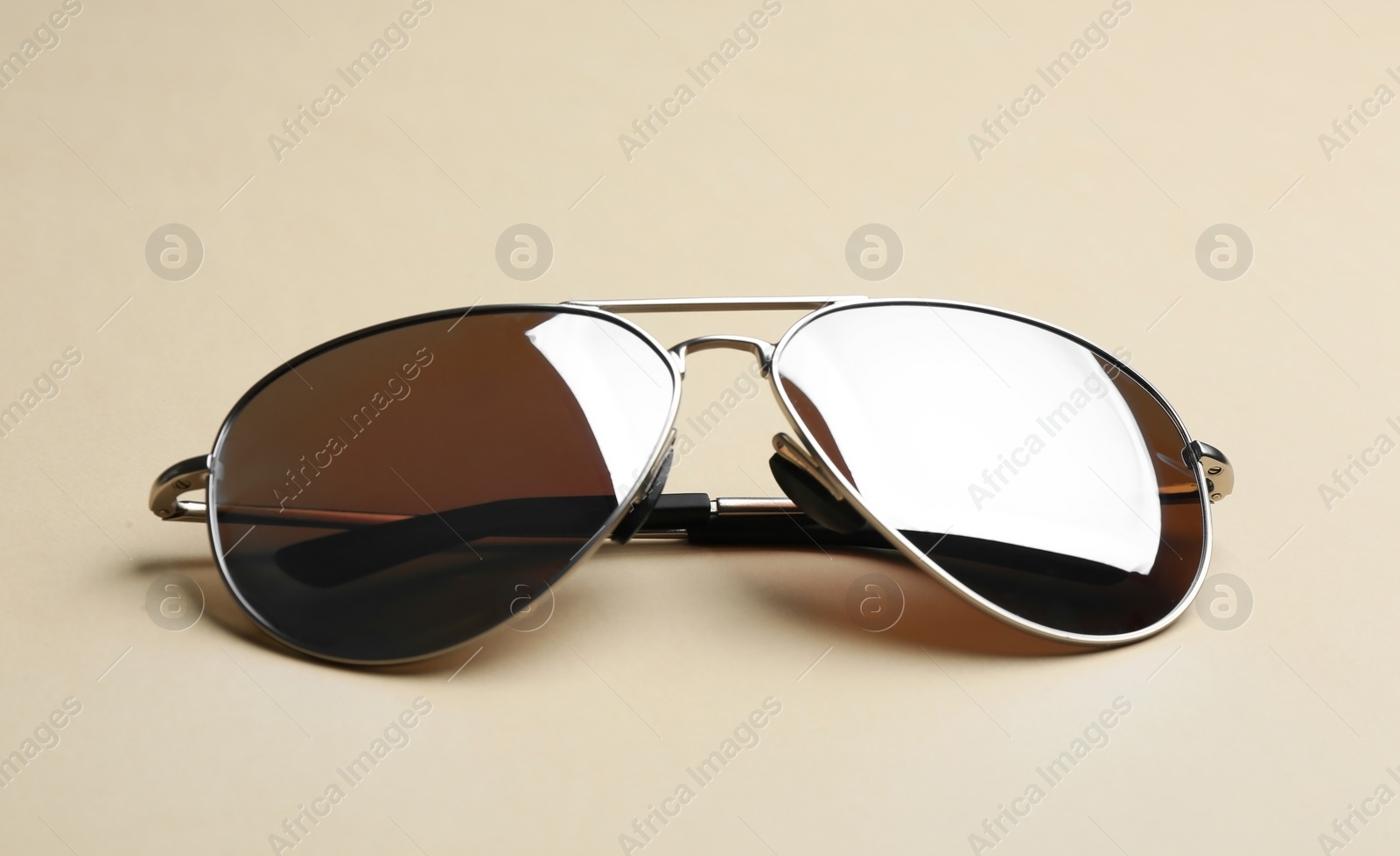 Photo of Stylish sunglasses on beige background. Fashionable accessory