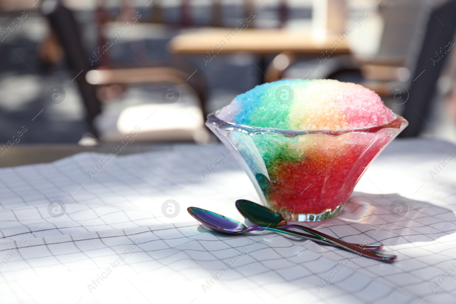 Photo of Rainbow shaving ice in glass dessert bowl and spoons on table outdoors