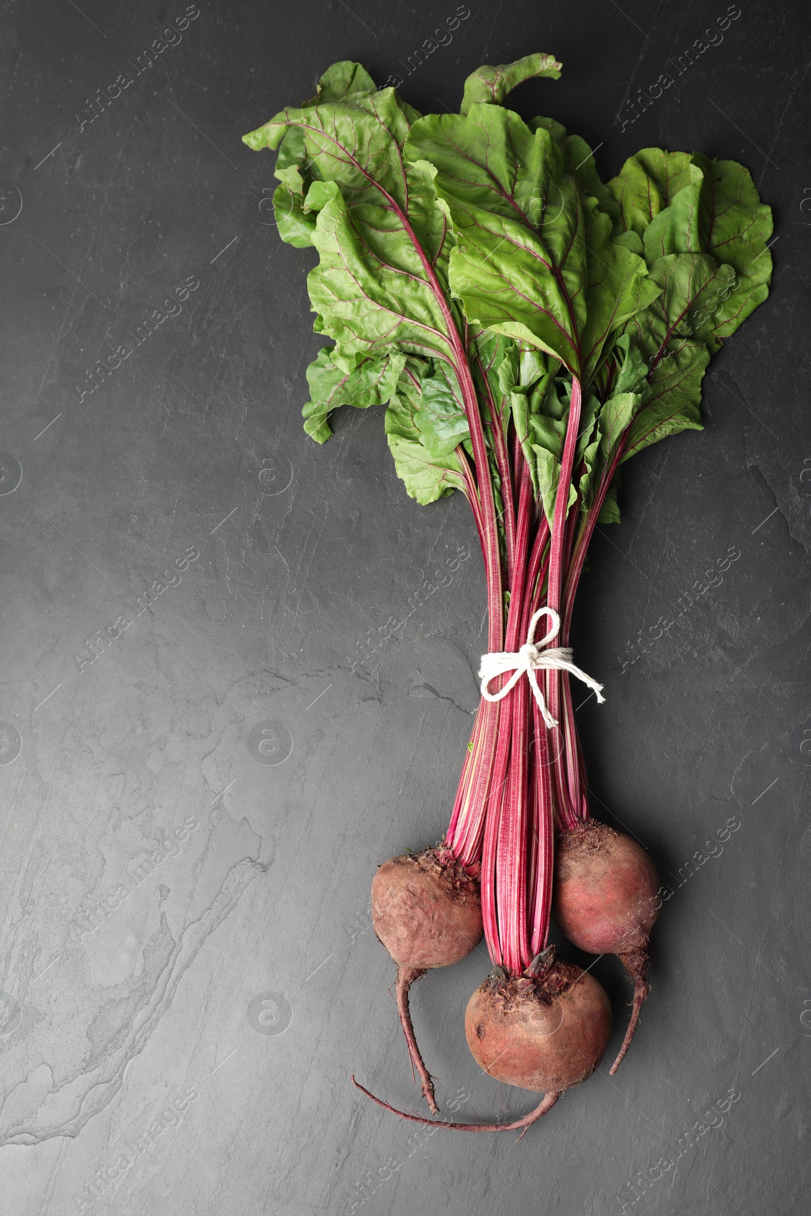 Photo of Raw ripe beets on black slate table, top view