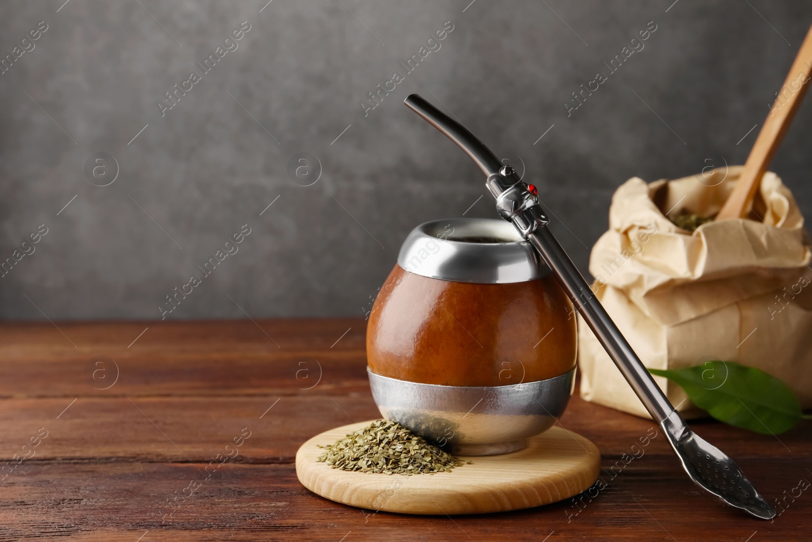 Photo of Calabash with mate tea and bombilla on wooden table. Space for text