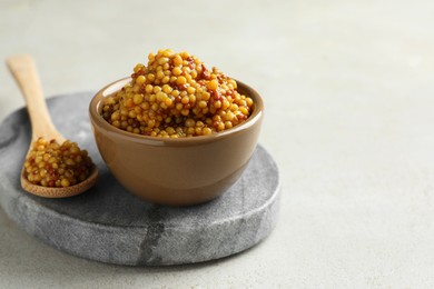 Photo of Bowl and spoon with whole grain mustard on light table. Space for text