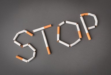 Word Stop made of cigarettes on dark grey background, top view. Quitting smoking concept