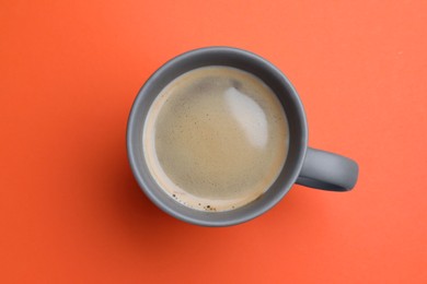 Photo of Grey mug of freshly brewed hot coffee on orange background, top view
