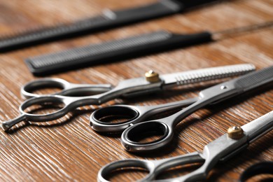 Photo of Hairdresser tools. Different scissors and combs on wooden table, closeup