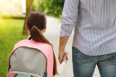 Image of Father taking his little daughter to school outdoors, back view