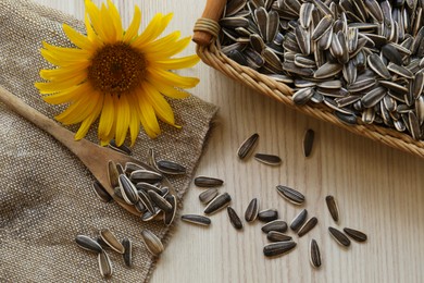 Sunflower seeds and flower on wooden table, flat lay