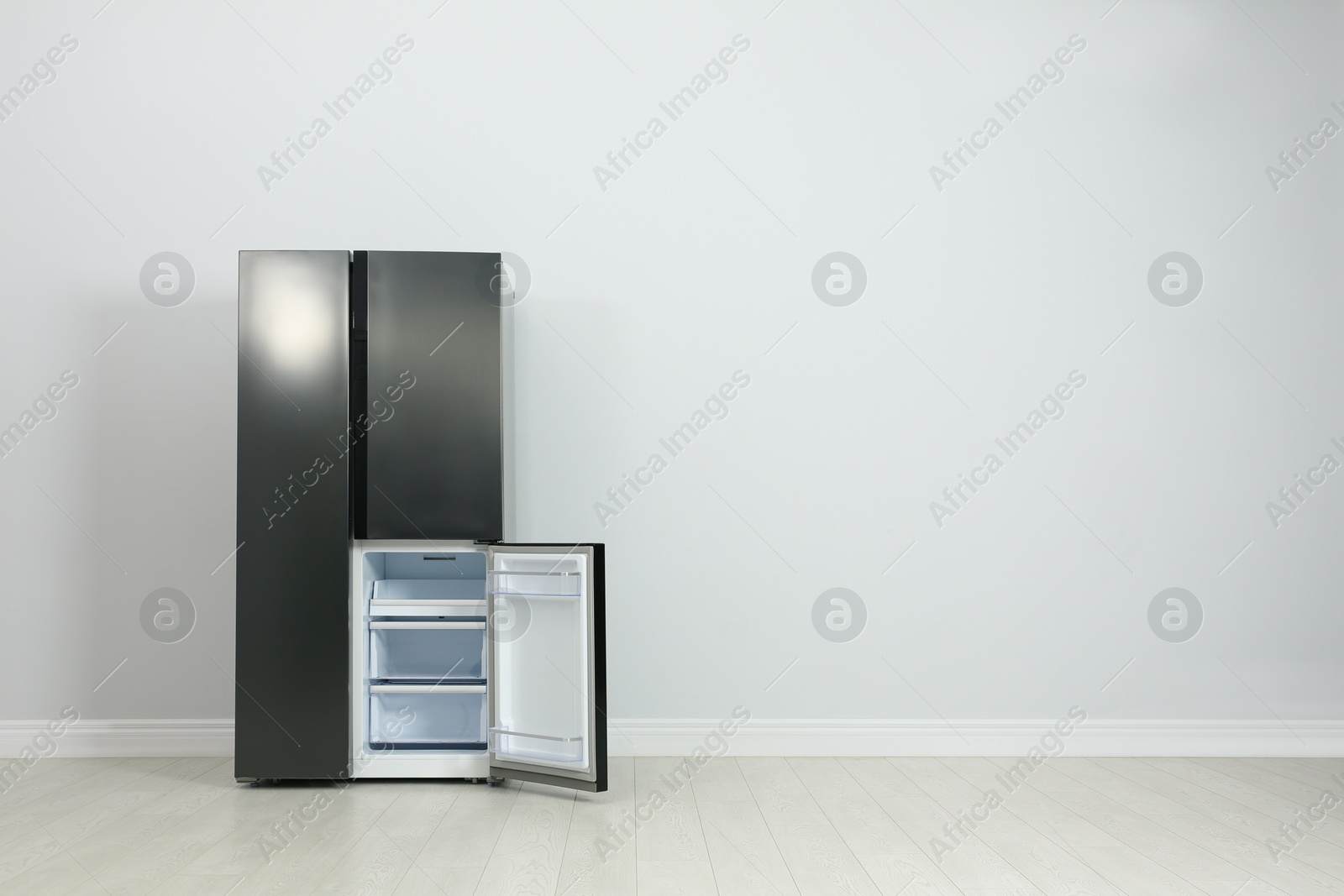 Photo of Modern refrigerator near light grey wall. space for text