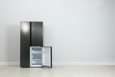 Photo of Modern refrigerator near light grey wall. space for text