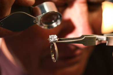 Photo of Professional jeweler evaluating beautiful ring, closeup view