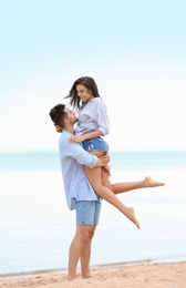 Photo of Happy young couple spending time together on beach near sea