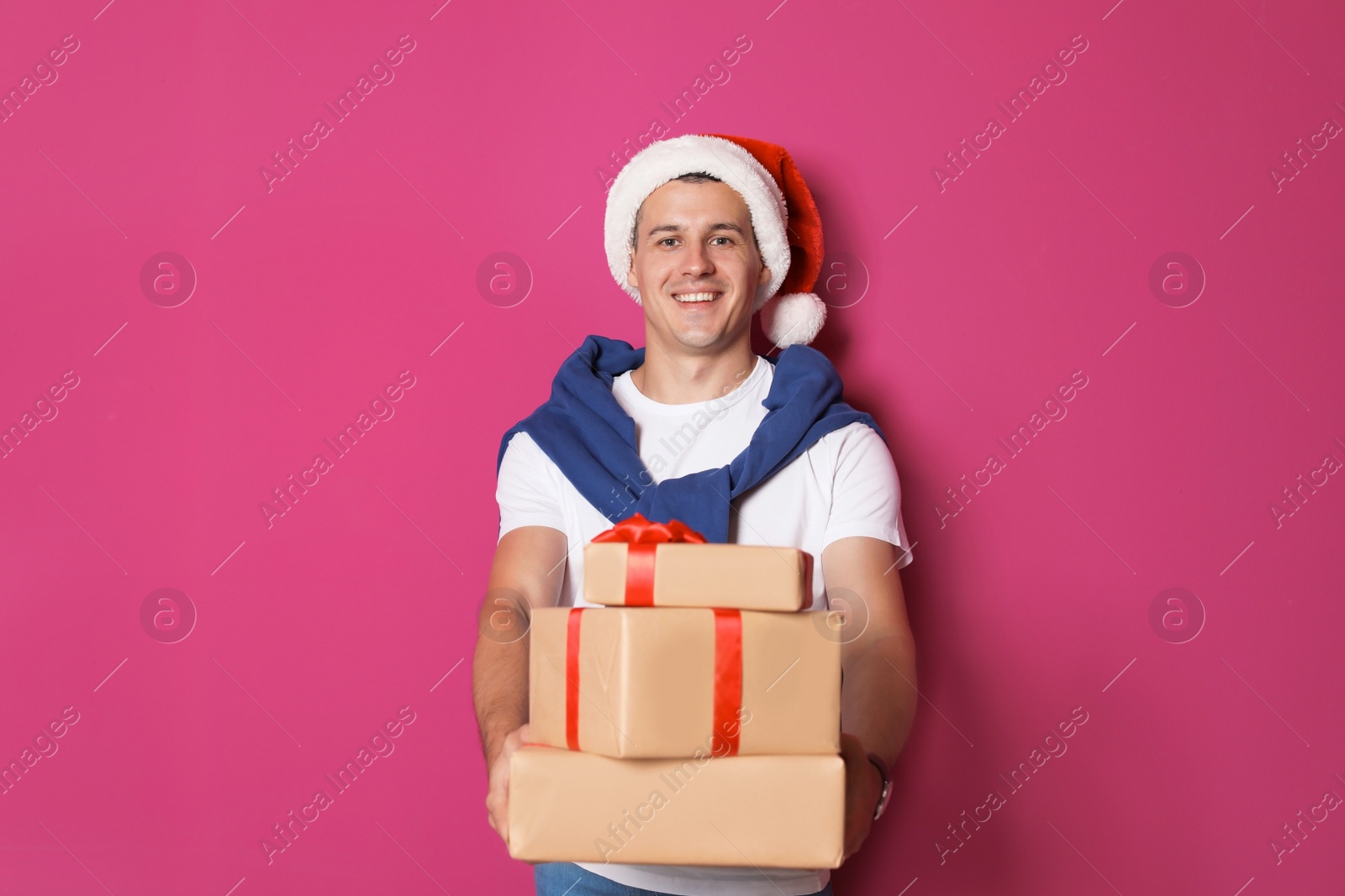 Photo of Young man with Christmas gifts on color background