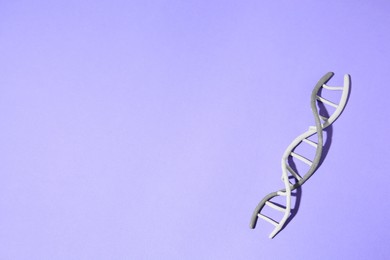 Photo of Plasticine model of DNA molecular chain on violet background, top view. Space for text