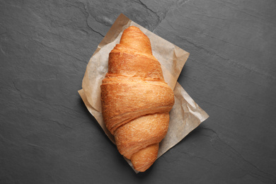 Tasty fresh croissant on black table, top view