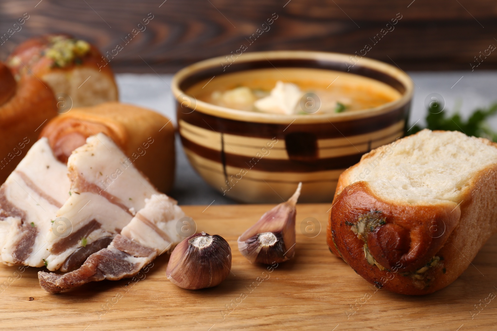 Photo of Delicious pampushky (buns with garlic) and salo served for borsch on table, closeup. Traditional Ukrainian cuisine