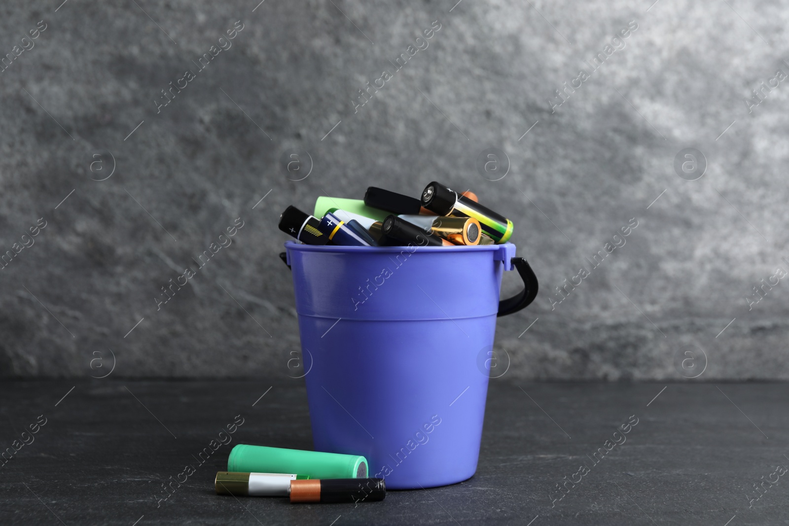 Image of Used electric batteries and bucket on dark table