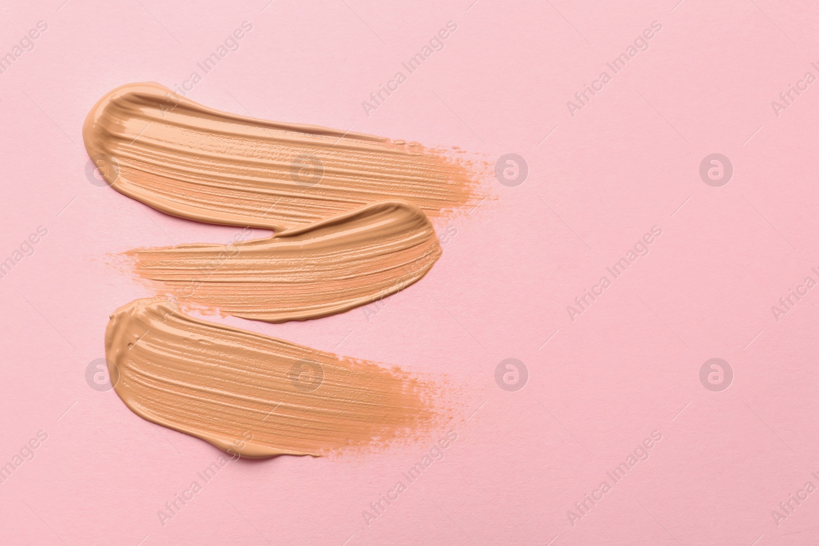 Photo of Sample of liquid skin foundation on pink background, top view. Space for text