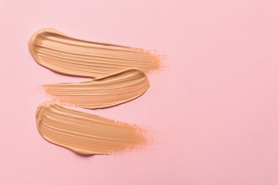 Sample of liquid skin foundation on pink background, top view. Space for text