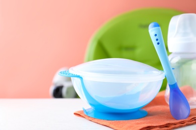 Photo of Set of plastic dishware on white wooden table. Serving baby food