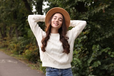 Photo of Beautiful young woman in stylish warm sweater and hat outdoors