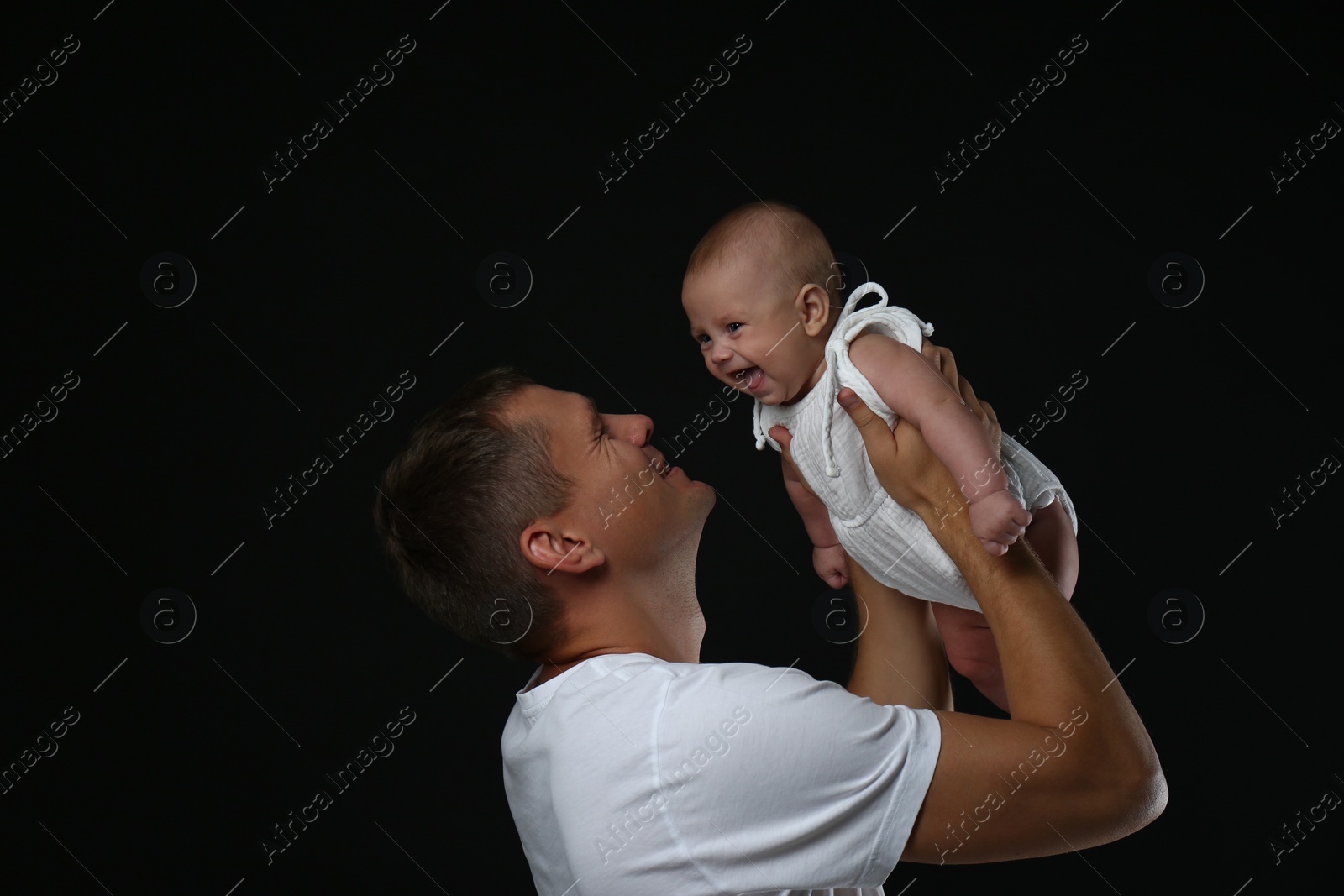 Photo of Happy father with his little baby on black background