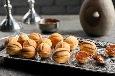 Homemade walnut shaped cookies with boiled condensed milk on grey table, closeup