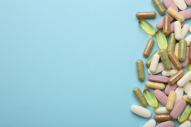 Photo of Different vitamin pills on light blue background, flat lay. Space for text