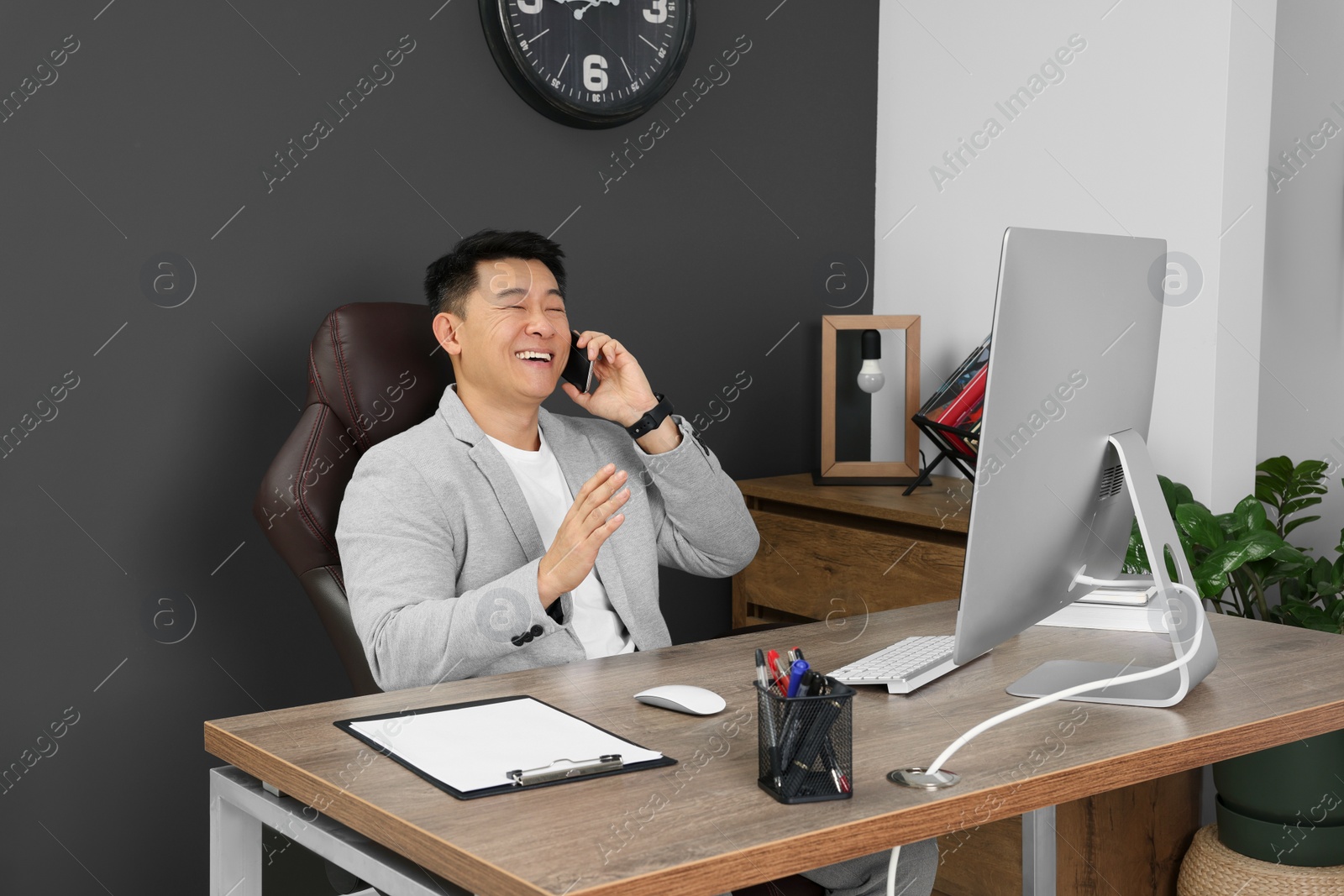 Photo of Happy boss talking on phone in his office