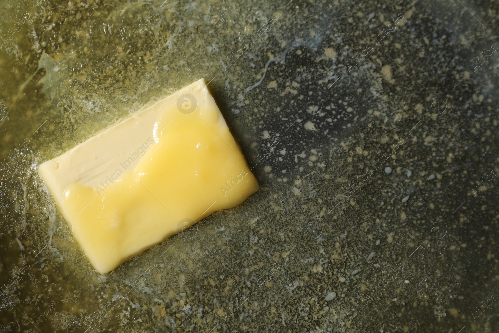 Photo of Melting butter in frying pan, top view. Space for text