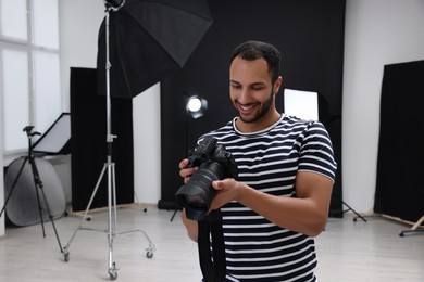 Photo of Young professional photographer with camera in modern photo studio, space for text