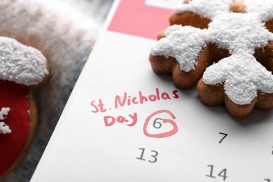 Photo of Saint Nicholas Day. Calendar with marked date December 06 and gingerbread cookies, closeup