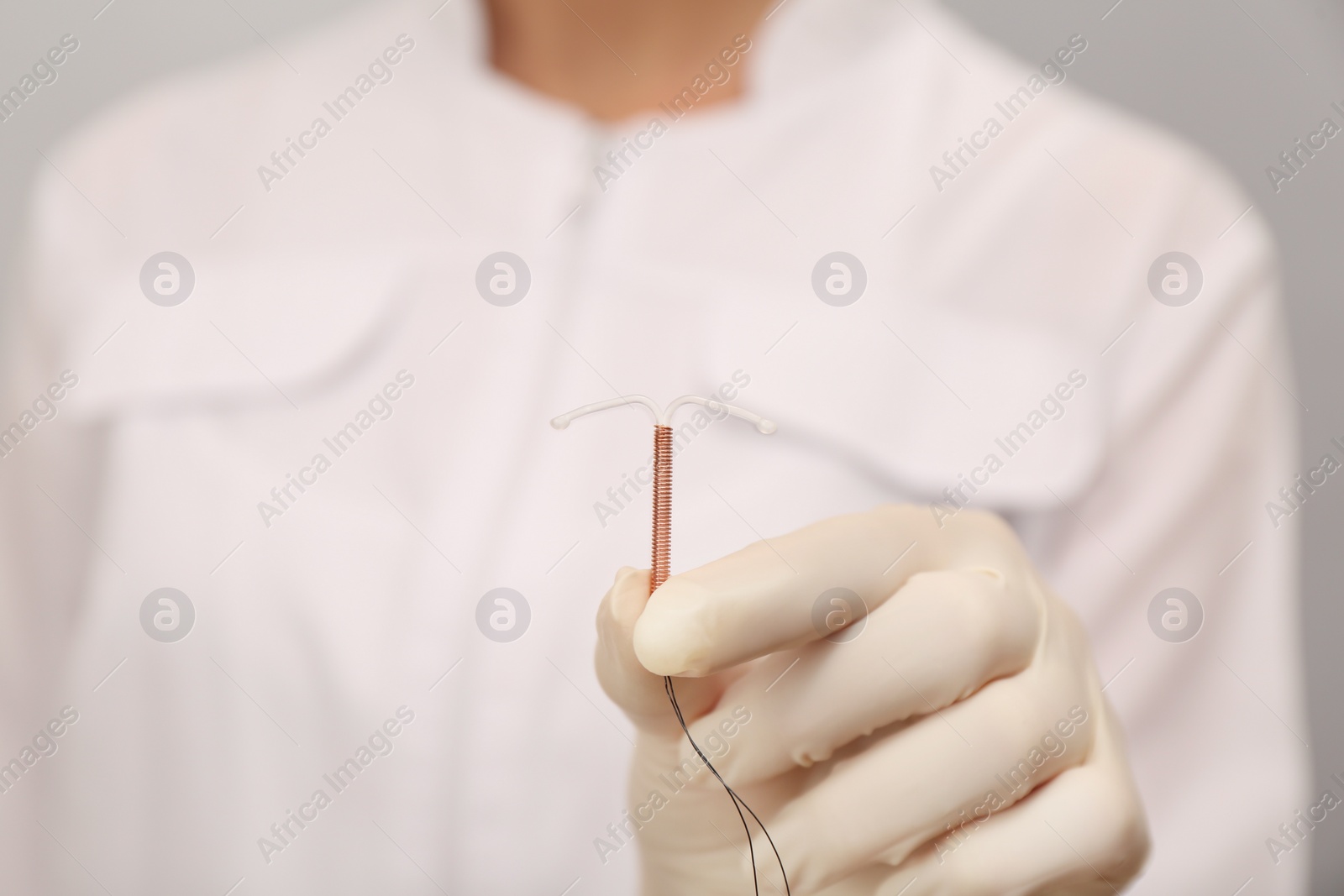 Photo of Doctor holding T-shaped intrauterine birth control device, closeup