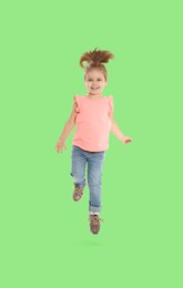 Happy cute girl jumping on light green background