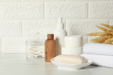 Different bath accessories, personal care products and spikelets on white table near brick wall