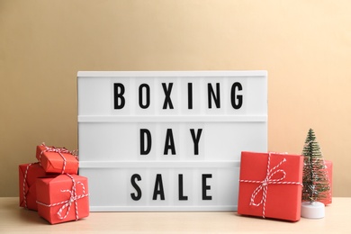 Photo of Composition with Boxing Day Sale sign and Christmas gifts on white table against beige background