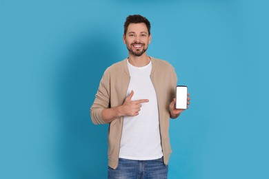 Happy man with phone on light blue background