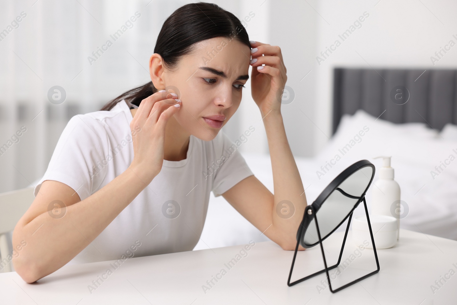 Photo of Woman with dry skin looking at mirror indoors