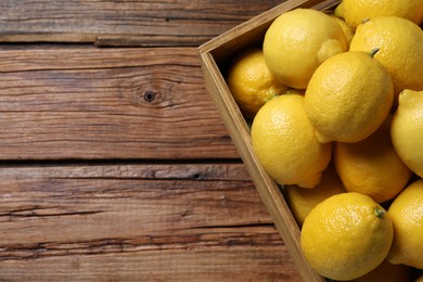 Photo of Fresh lemons in crate on wooden table, top view. Space for text