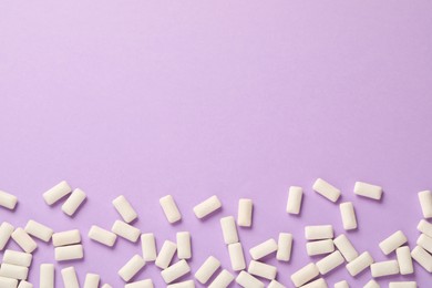 Photo of Many chewing gum pieces on violet background, flat lay. Space for text