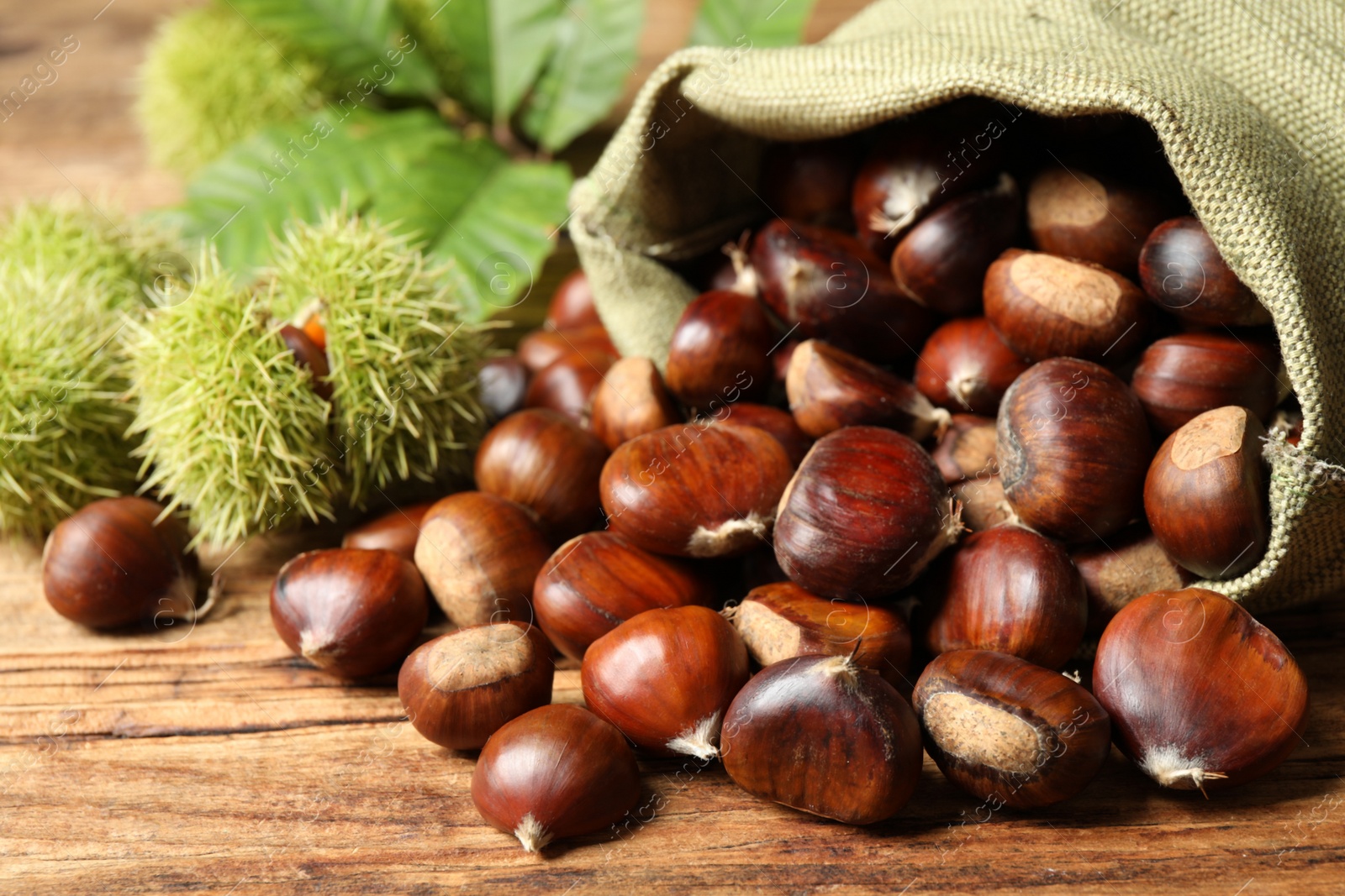 Photo of Fresh sweet edible chestnuts on wooden table, closeup