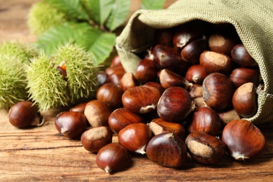 Fresh sweet edible chestnuts on wooden table, closeup