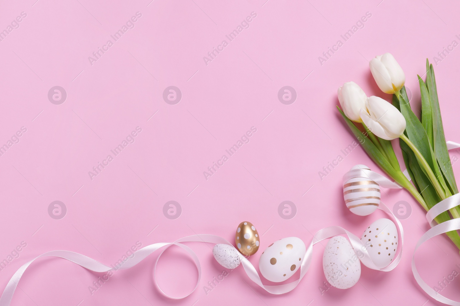 Photo of Many painted Easter eggs, tulip flowers and ribbon on pink background, flat lay. Space for text