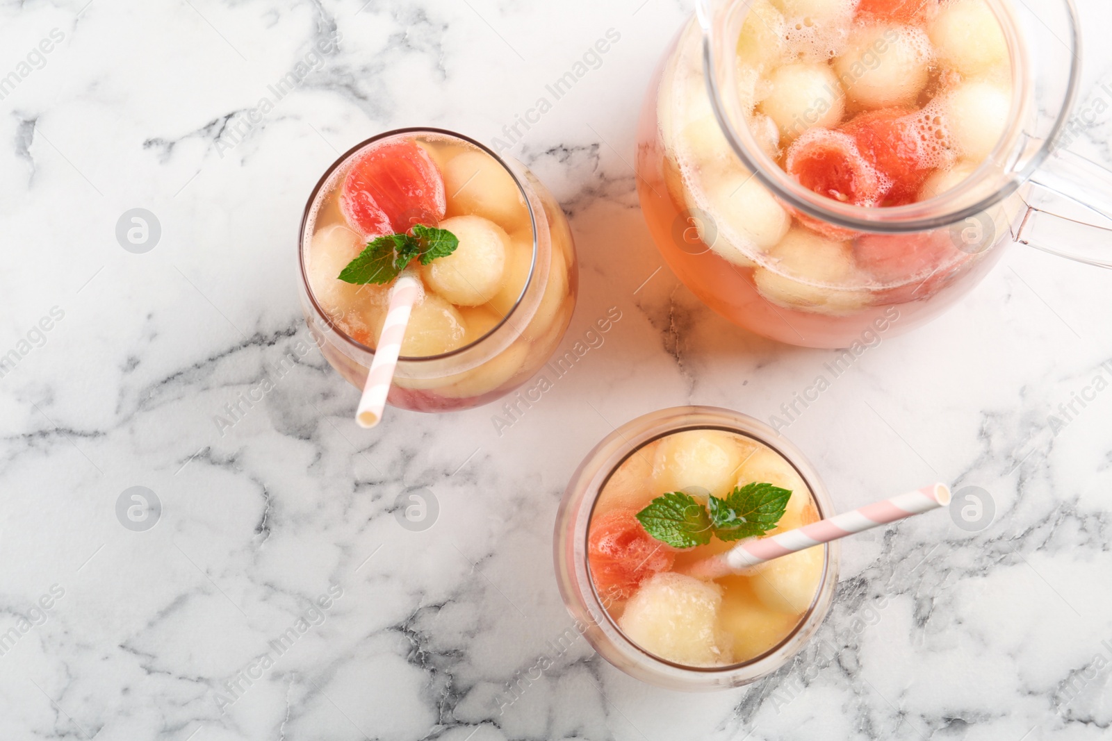 Photo of Melon and watermelon ball cocktail with mint served on white marble table, flat lay