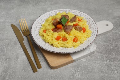 Photo of Delicious pilaf with meat served on light grey table